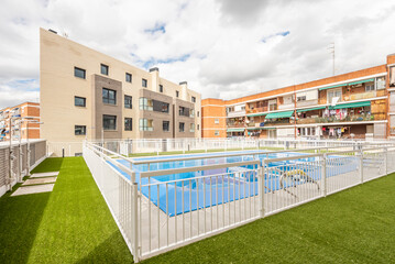 Facades of urban residential houses with community pool and artificial grass