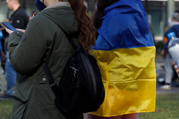Fototapeta na wymiar Ukrainian flag carried by a girl on her back at an anti-war demonstration in Berlin