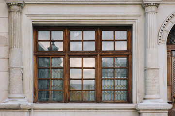 Old vintage window on the facade of the house with cornice and gray columns. Lviv, Ukraine.