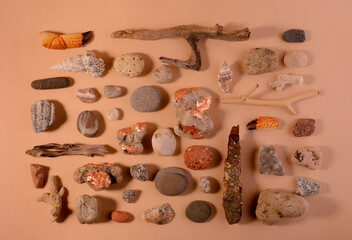 Set of various sea stones and wooden sticks against sand color background top view 