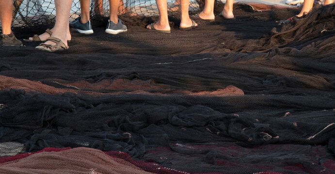 Big fishing net laying on the dock and fishermen legs