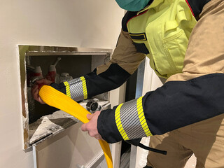Firefighter places hose in dry column
