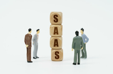 On a white background, figures of businessmen and wooden cubes with the inscription - SAAS