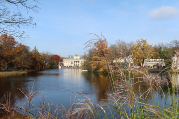 Fototapeta premium Autumn, fall time in Warsaw's Royal Baths Park. Warsaw, Poland. Palace on the Water (or Lazienki Palace, Palace on the Isle). View from the side of the pond.