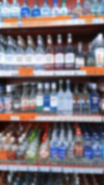 Abstract blur image of supermarket background. Defocused shelves with bottles of alcohol, vodka, cognac, brandy, wine, beer, champagne. Grocery Store. Retail industry. Inflation and crisis concept.