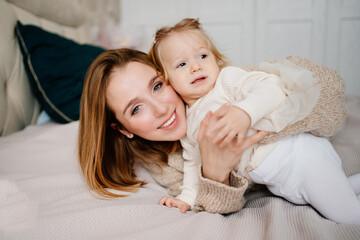 Cute mom and baby daughter lie down, play and hug in bed. games with children. 