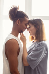 Naklejka premium Portrait of a multiracial couple, boyfriend and girlfriend face to face, stand near the window