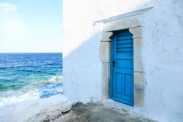 Traditional white building with blue door at the seaside. Mykonos island, Greece - Powered by Adobe
