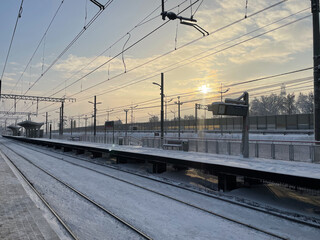 Fototapeta na wymiar Empty railway platform without passengers in winter at the sunset.