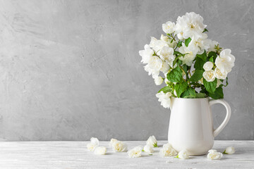 Fototapeta na wymiar White jasmine blossom flowers bouquet in a vase on white wooden table. Still life