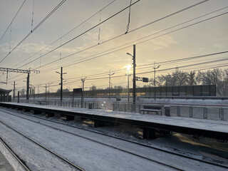 Fototapeta na wymiar Empty railway platform without passengers in winter at the sunset.