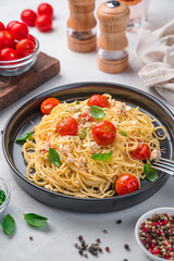 Fetapasta, spaghetti with baked feta with cherry tomatoes and herbs in a black plate.