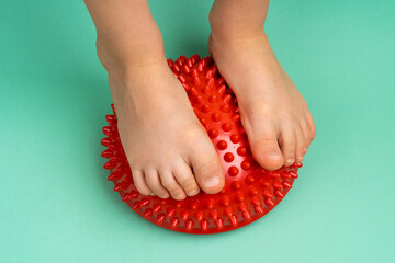 children's feet with a red balancer on a light green background, treatment and prevention of flat...