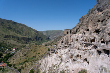 Fototapeta na wymiar monastery in the mountains of georgia where there are caves and passages along the mountain, above them there is a blue sky.