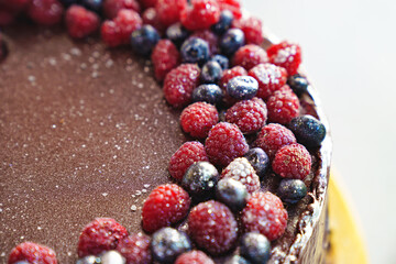 part of a round chocolate cake with fresh raspberries and blueberries