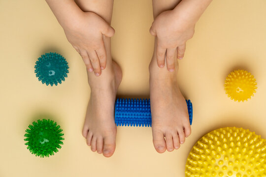 blue needle roller for massage and physiotherapy on a beige background with the image of a child's foot, massage balls and a balancer, the concept of prevention and treatment of hallux valgus