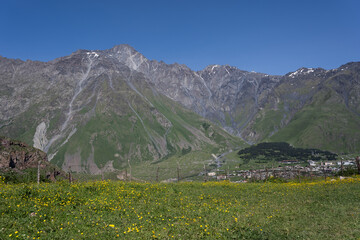 Fototapeta na wymiar the Kazbegi mountain ranges in Georgia are green and have a clear sky above them.