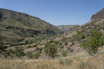 the Kazbegi mountain ranges in Georgia are green and have a clear sky above them.