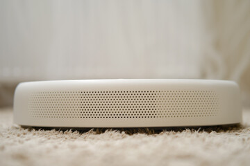 White robot vacuum cleaner on a fleecy carpet, close-up