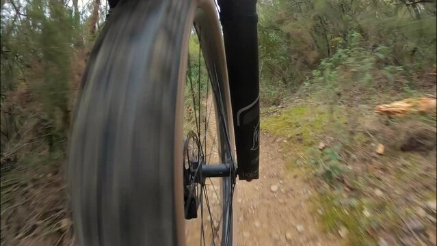 Riding an outdoor mountain bike on a rocky and sandy trail in a Mediterranean forest in Girona, Catalonia, front wheel point of view