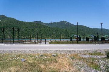 recreation area by the lake in the mountains where there is a yard, some cottages and children's slides, benches and other beach recreation