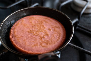 hotcake sabor fresa recién volteado en sartén negro individual al fuego
