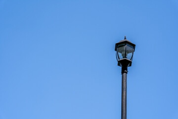 Fototapeta na wymiar a black metal light lantern on a pole with a blue sky in the background