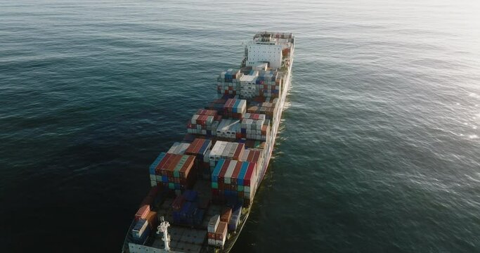 Aerial close-up fly over view of a container ship out at sea