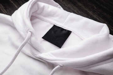 Blank clothing label on the texture of a white sweater hoodie. Label with empty space for text