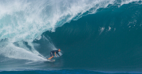 Surfer surfing big ocean barrel tube wave at Pipeline in north shore of Hawaii's Oahu island pro...