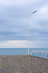 beach with lantern and concrete fence where the sea and the horizon above which the dramatically beautiful sky is visible in the background