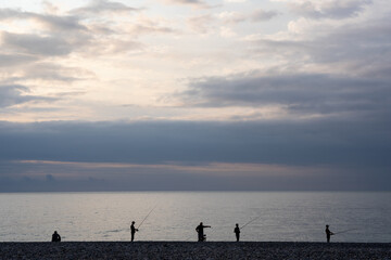 fabulously romantic sunset at sea with dark silhouettes of anglers on the horizon