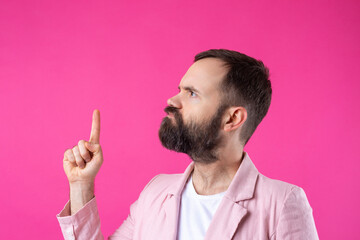 Handsome man with a beard in a pink jacket is thinking over an isolated red background.