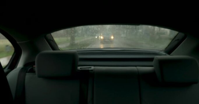 Car rear window view with following cars on a rainy winter day