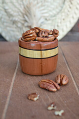 BARRIL DE BARRO CON NUECES ENTERAS SOBRE FONDO DE MADERA