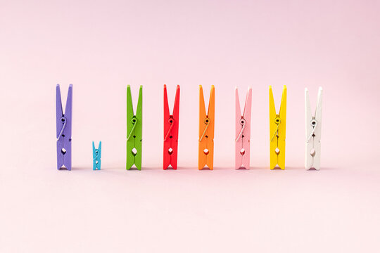 Colorful laundry clips lined up on pastel pink background. Minimal creative opposite concept.