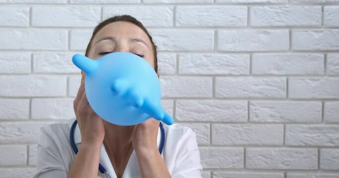 Present from medical gloves. A doctor makes a present from medical glove and blow into it in the room.