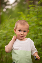Cute little boy in the forest against the background of grass