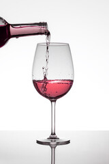 A bottle filling a glass of rose wine
