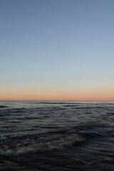 Sunset on the sea. Dark waters and blue sky