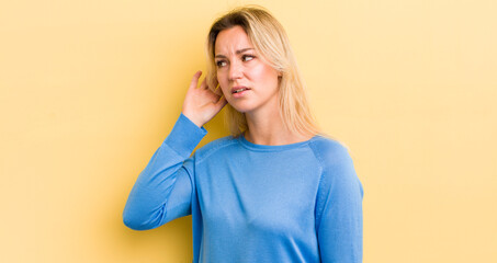 blonde caucasian woman looking serious and curious, listening, trying to hear a secret conversation...