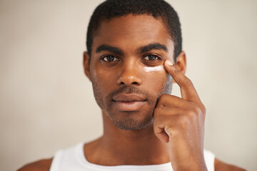 He takes care of his skin. A young man applying face cream.