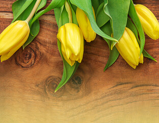 Yellow tulips arrangement on wooden background. Flat lay top view with copy space.