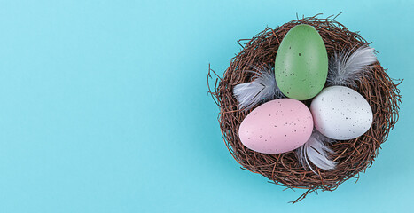 Easter eggs lie in a nest arrangement on blue background. Flat lay top view with copy space. Happy Easter holiday.
