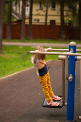 Blond charming girl in casual closing playing on the playground summertime