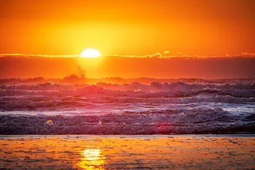 Poster A setting sun reflects off of ocean waves creating a colorful sunset sky © Harrison
