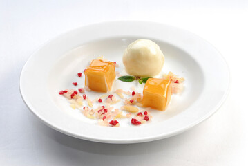 Vanilla ice cream dessert with honey covered jelly cubes and raspberry pieces in white deep plate