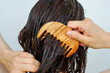 Woman combing hair treatment through hair.