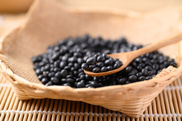 Fototapeta na wymiar Black soybean seeds in wooden spoon and basket, Food ingredients