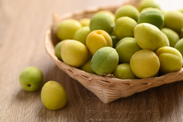 Apricot green with yellow (Japanese apricot) in basket on wooden background